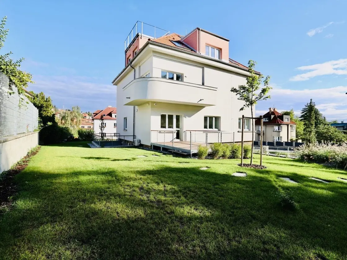Bílá vila se střešní terasou a udržovanou zahradou